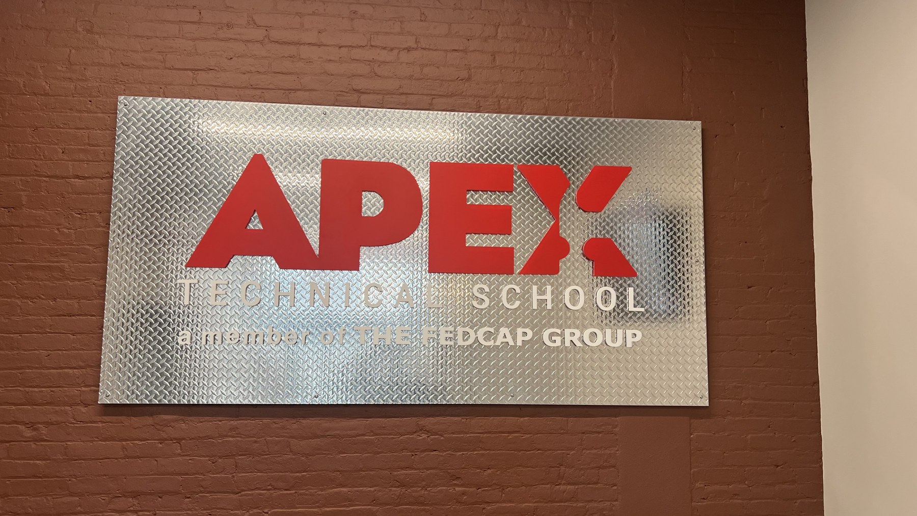 Dimensional logo and lettering mounted on a patterned metal panel