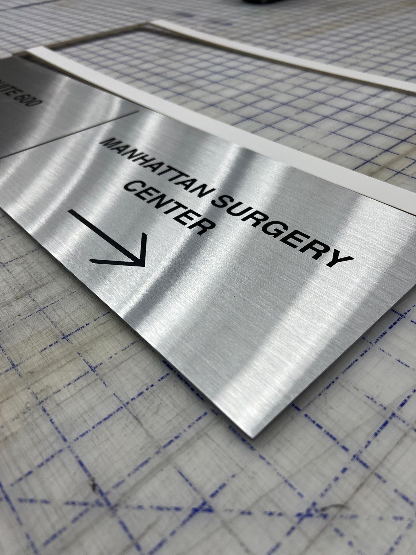 Brushed metal directional sign with black lettering and an arrow
